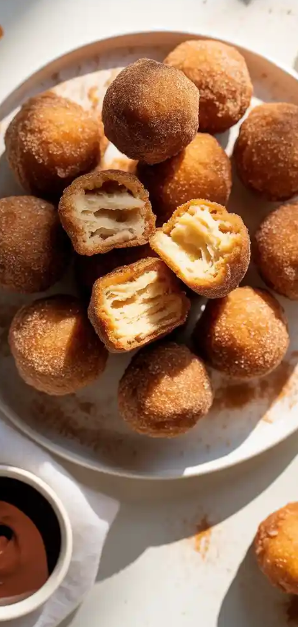 Freshly cooked bite-sized churros arranged neatly on a plate with dipping sauces, perfect for kids and family desserts.