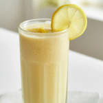 Refreshing lemon ginger smoothie with ice and yogurt served in a clear glass