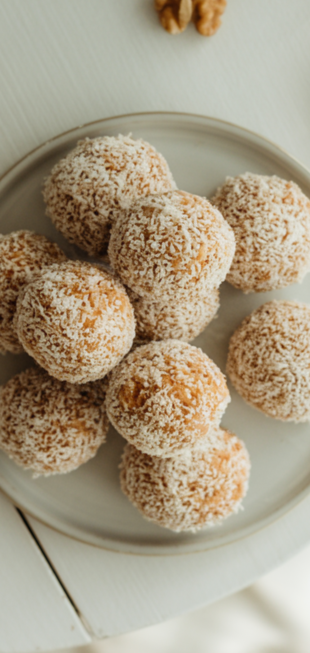 A child's hands are shown rolling the carrot cake mixture into a small, round ball. Their hands are slightly messy from the ingredients, with a mixing bowl visible in the background.
