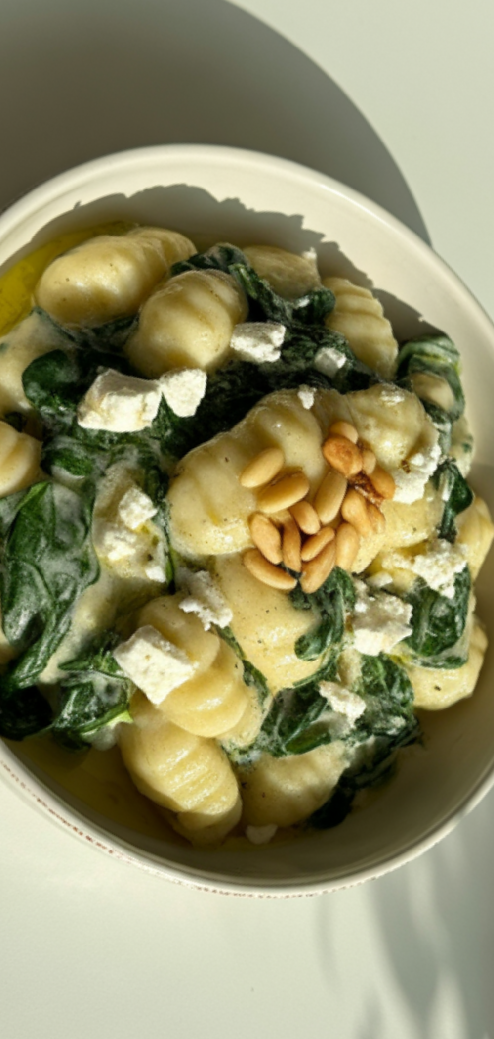 Top view of fluffy gnocchi in creamy sauce with spinach and feta, styled like a food blogger photo