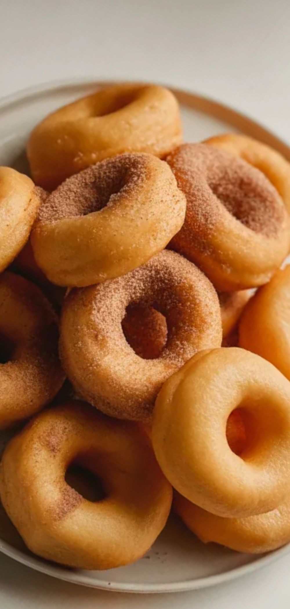 “Freshly cooked fluffy air fryer donuts on a simple white plate, slightly crumbly, ready to eat, cozy breakfast setting”