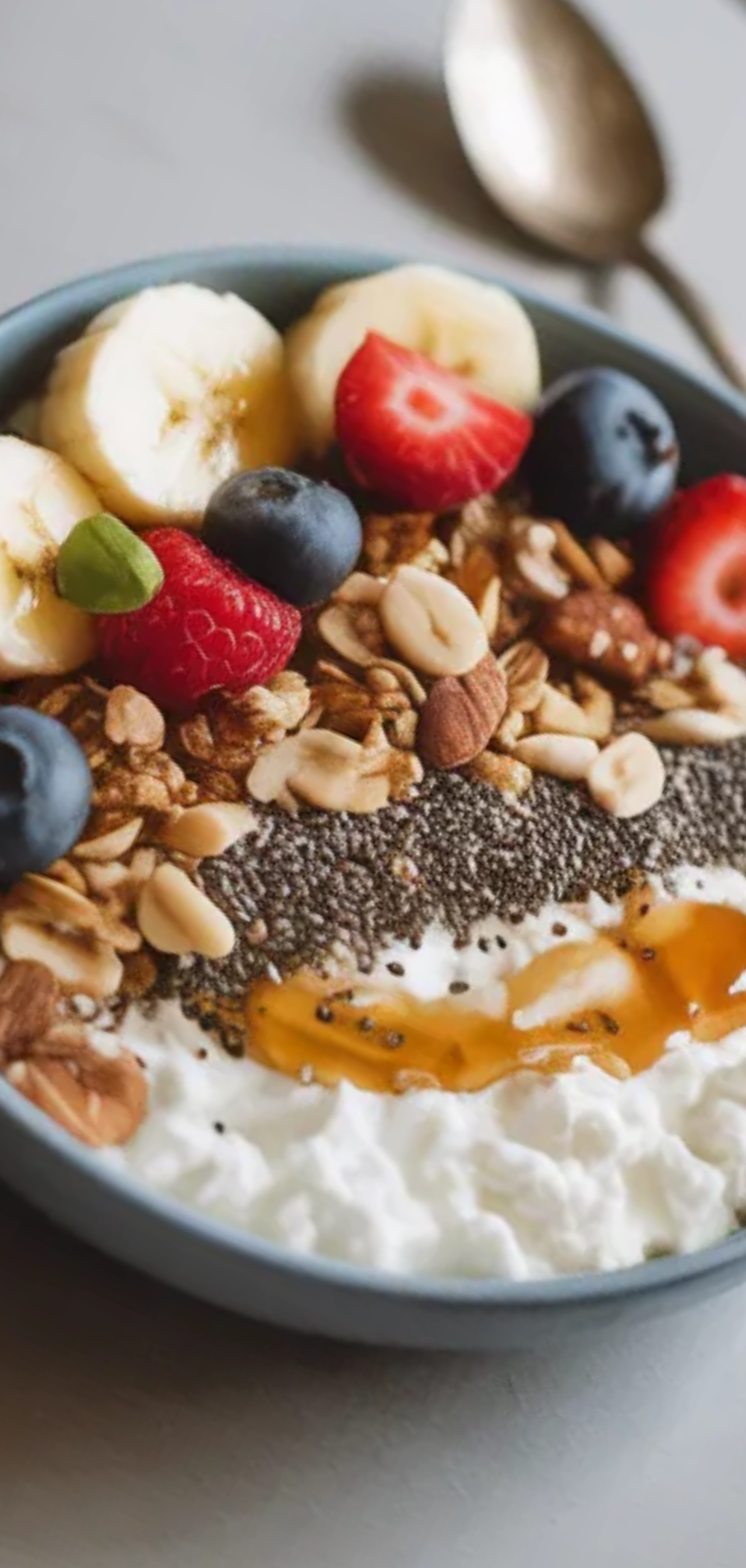 Healthy cottage cheese bowl with berries, banana, granola, and nuts arranged casually in a bowl on a bright white table, perfect for a quick protein-packed breakfast.