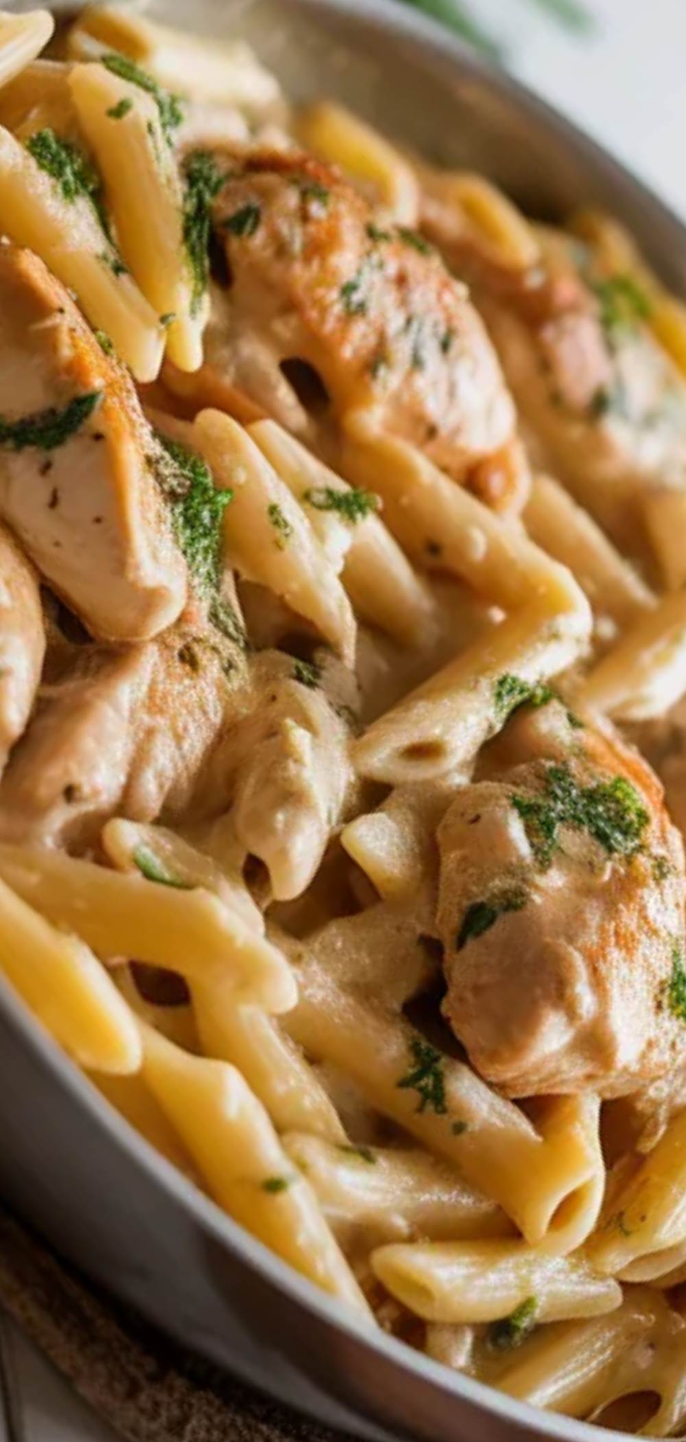 “Delicious creamy chicken pasta cooked in a skillet, with melted cheese and green parsley, styled like a cozy home-cooked meal”