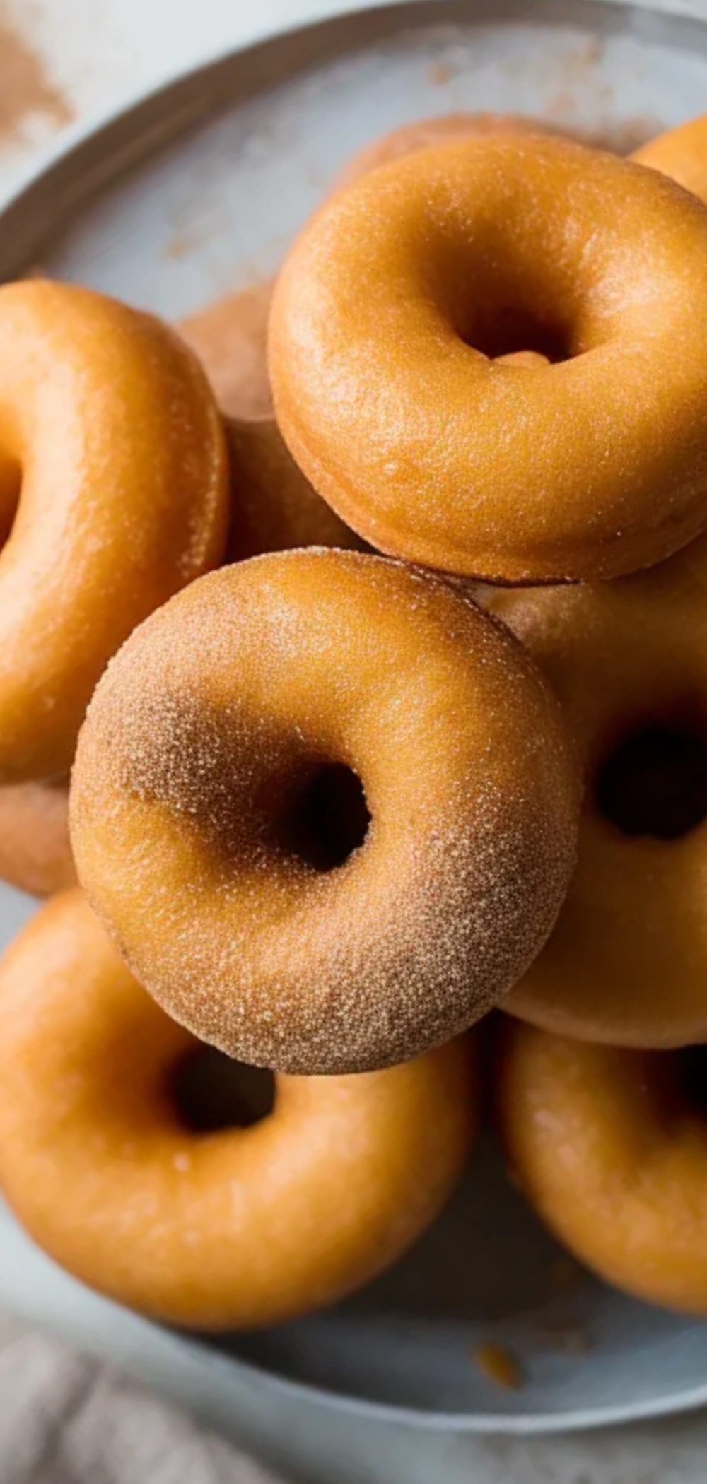 “Homemade air fryer donuts, golden and soft, arranged on a white table with minimal props, natural lighting, inviting and appetizing look”