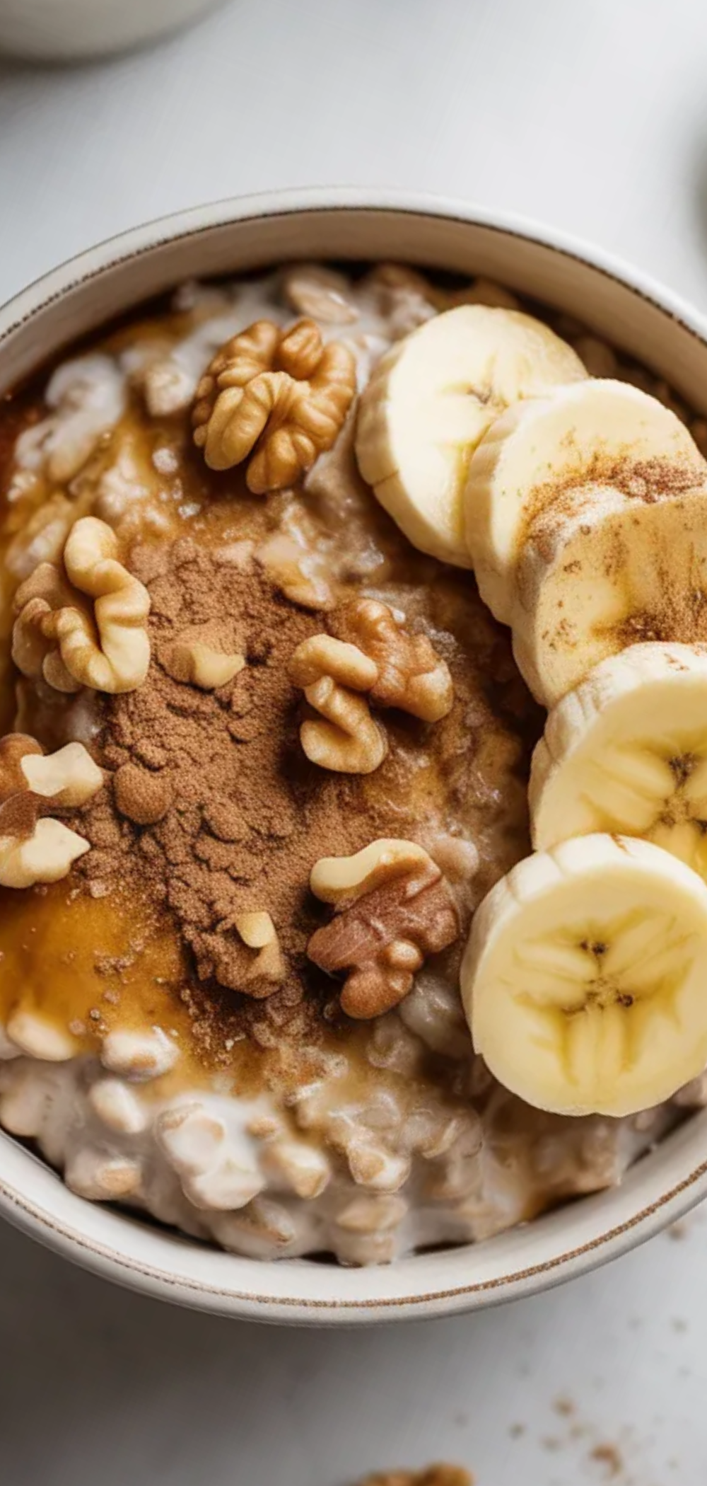 Close-up of cinnamon roll flavored overnight oats in a small white bowl with a spoon, cozy breakfast setting, fresh fruit topping, minimalistic background