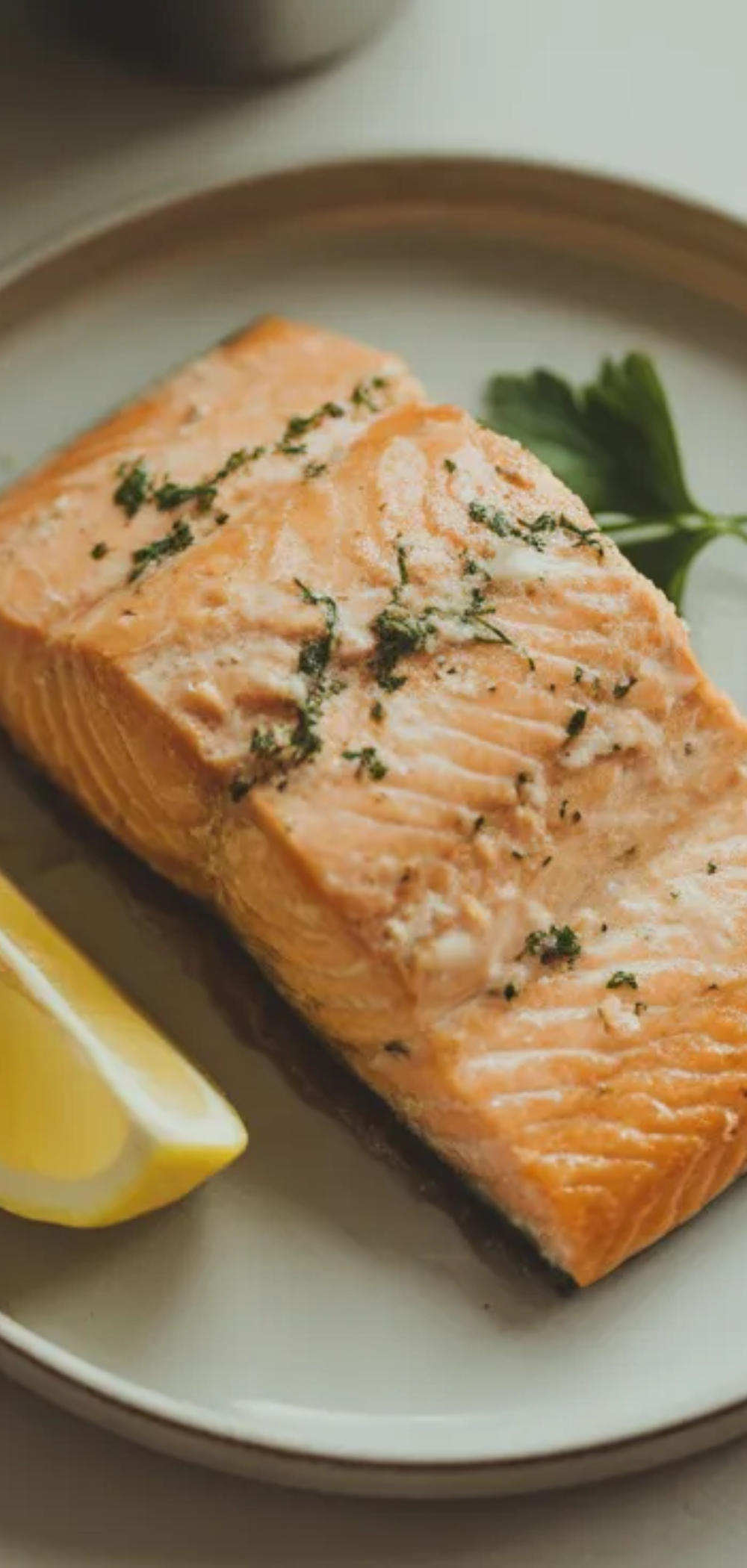 Healthy air fryer salmon dinner on a white plate with juicy flaky fish, lemon slice, and parsley, styled like a food blogger photo.
