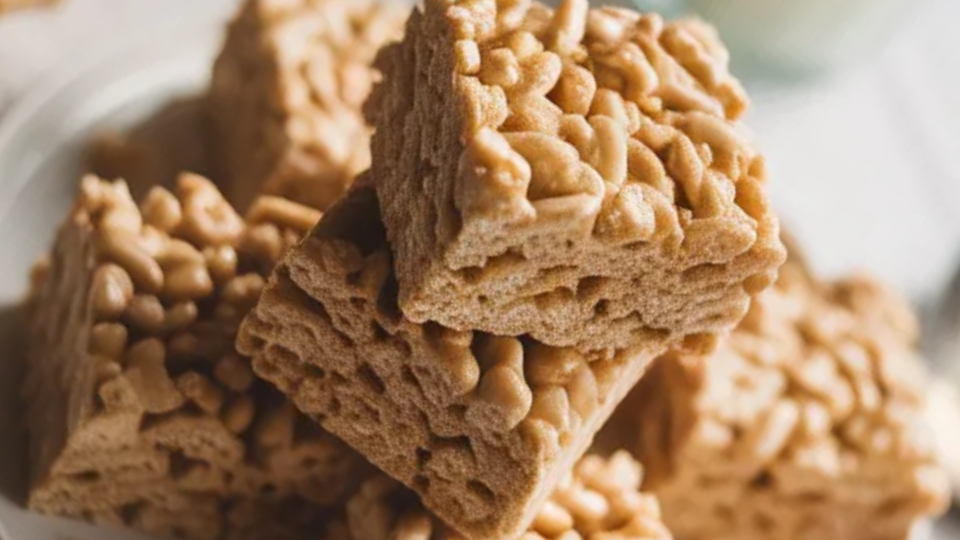 Brown butter Rice Krispies treats stacked on a white plate with soft natural lighting and a cozy homemade look