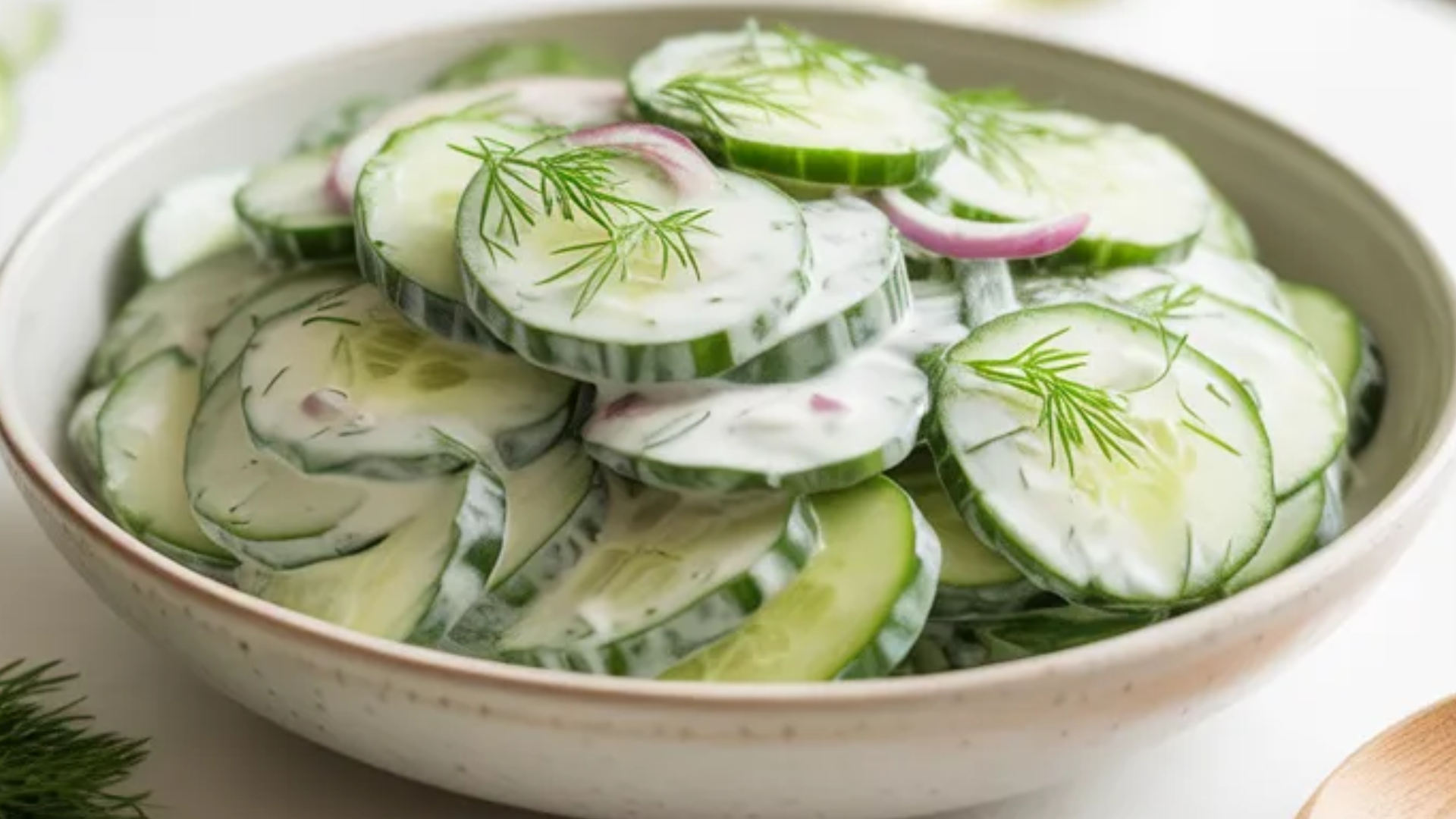 Creamy cucumber dill salad in a white bowl on a bright white table