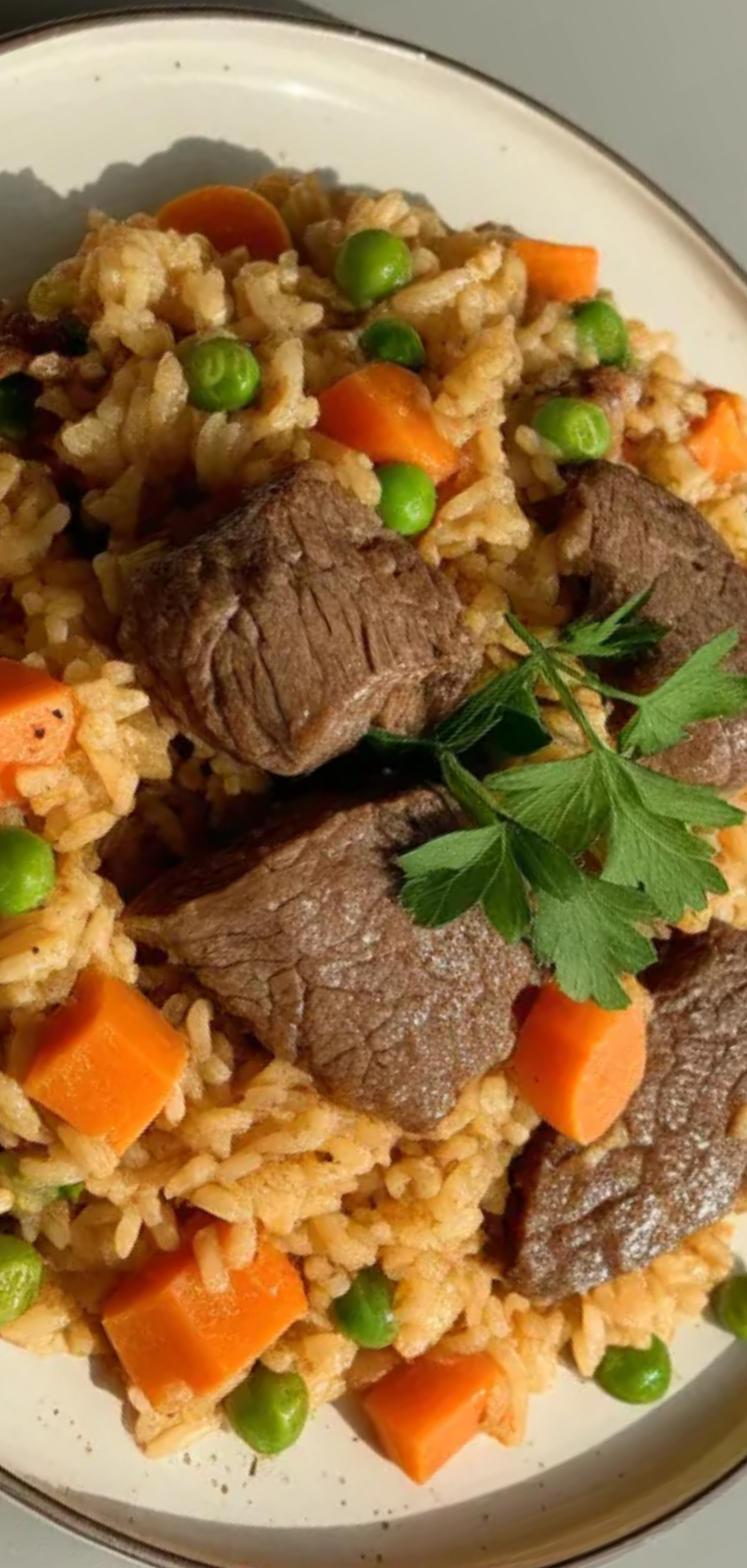 “Close-up of a hearty serving of One Pot Beef Rice on a white table, garnished with fresh parsley.”