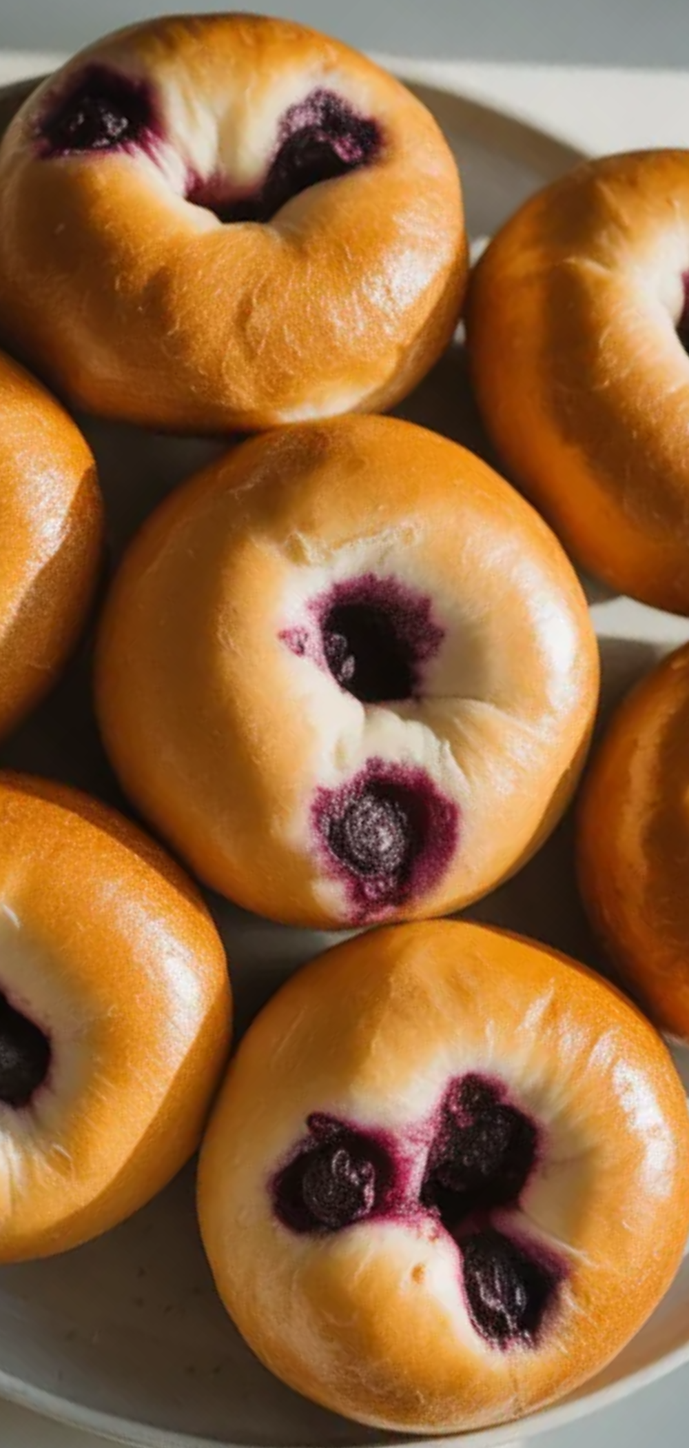 Soft and chewy blueberry bagels arranged on a clean white surface with natural light and a simple food photography style