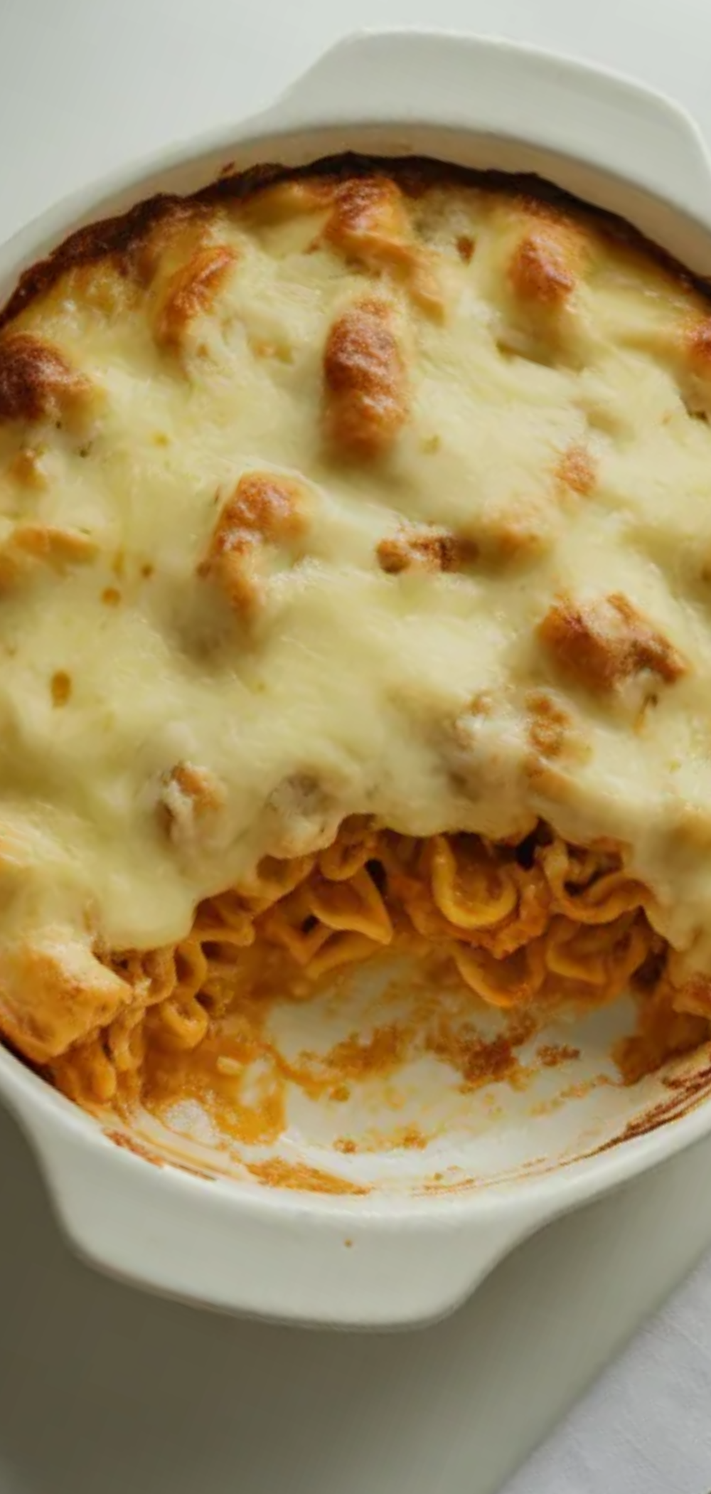 Comfort food cheesy pasta bake with creamy sauce and golden cheese topping styled on a bright white background