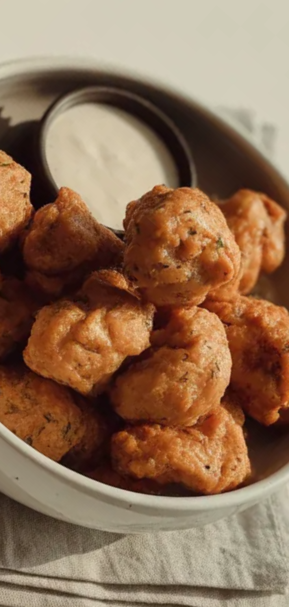 Golden brown air fryer chicken bites with seasoning in a minimal white setup with soft natural lighting