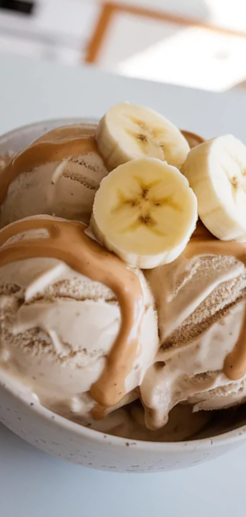 Close-up of creamy protein ice cream in a bowl with natural lighting and a simple minimal food blogger style setup