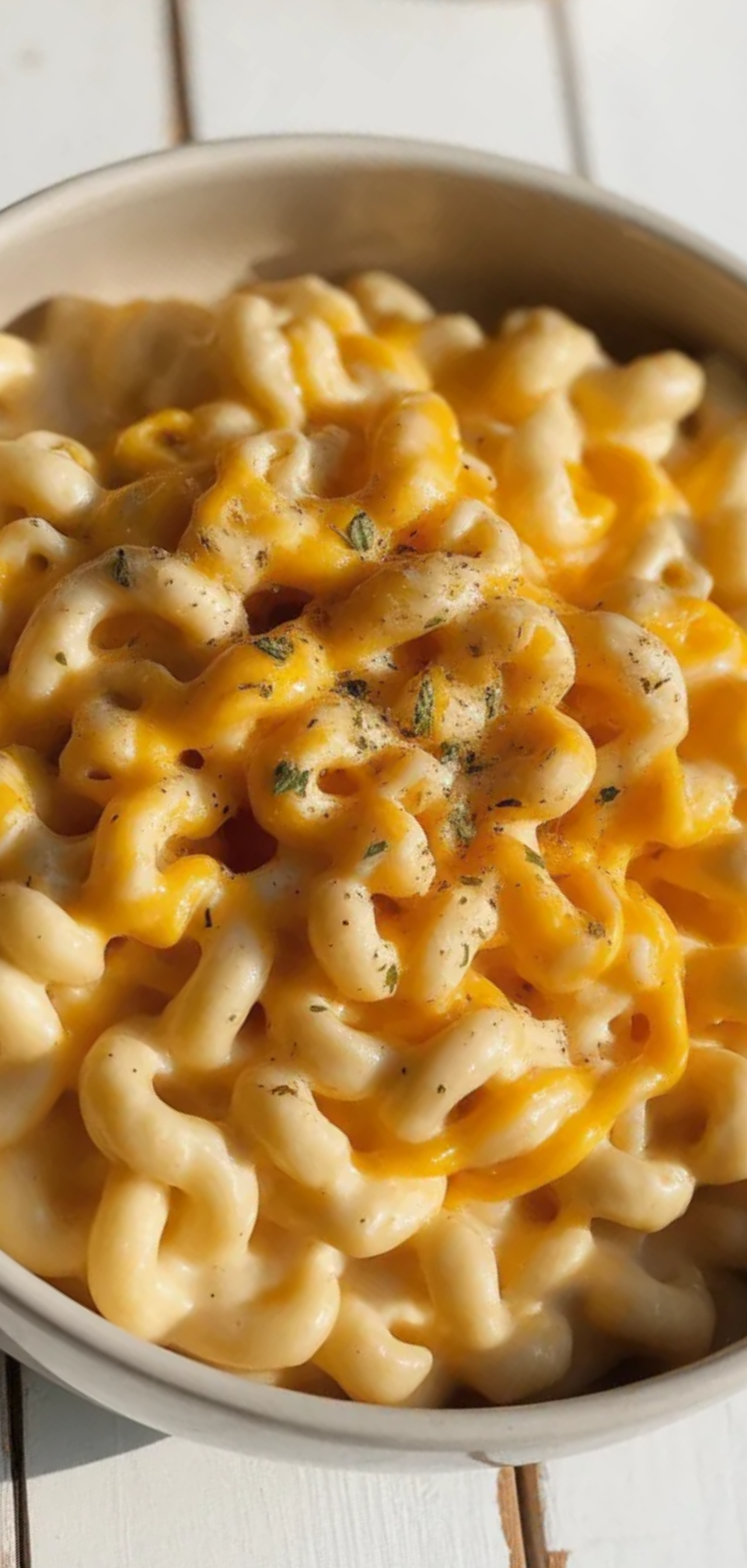 “Close-up of cheesy mac and cheese in a bowl, showing gooey, creamy pasta with herbs sprinkled on top, styled like a food blogger photo.”