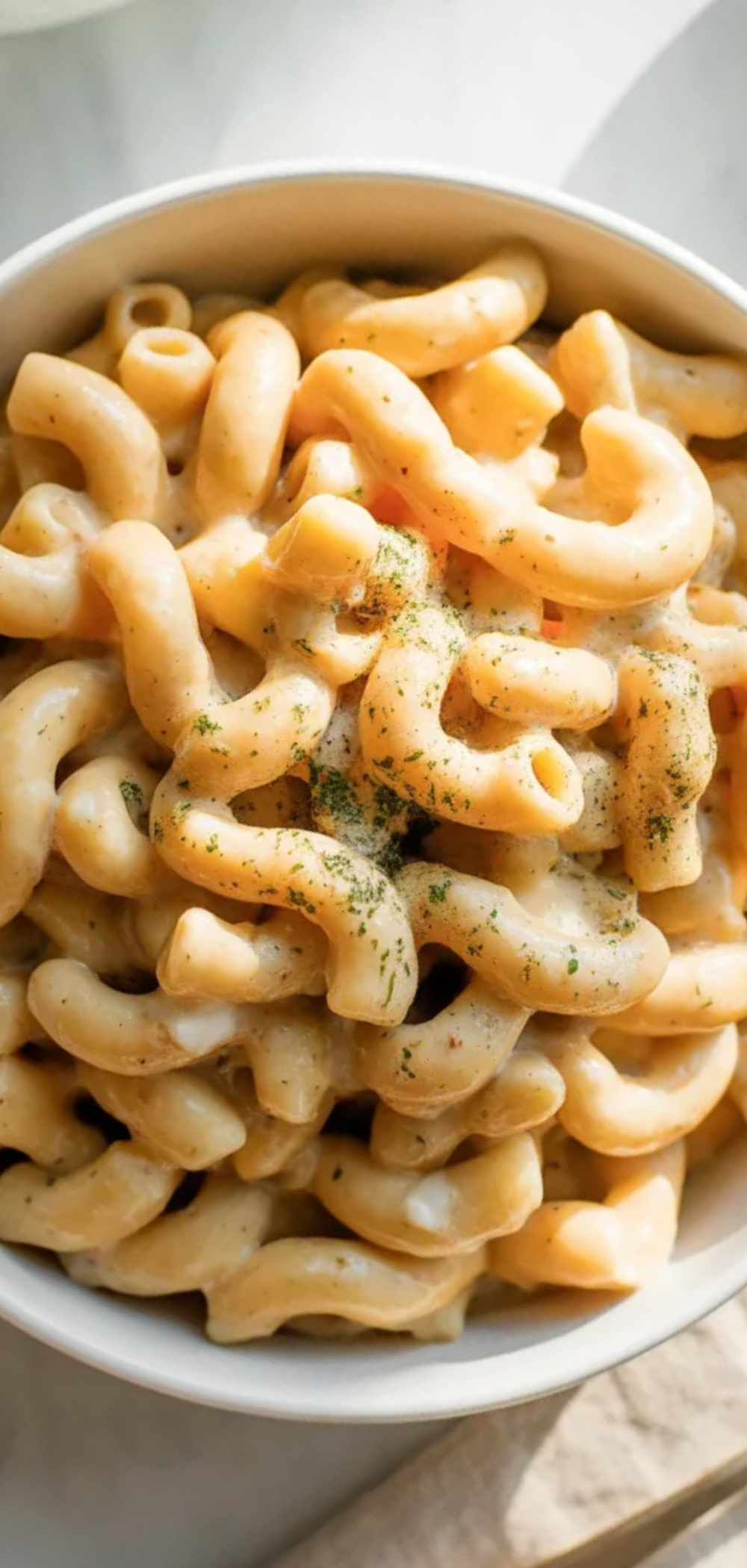 Healthy homemade mac and cheese served in a white dish with a fork and minimal styling