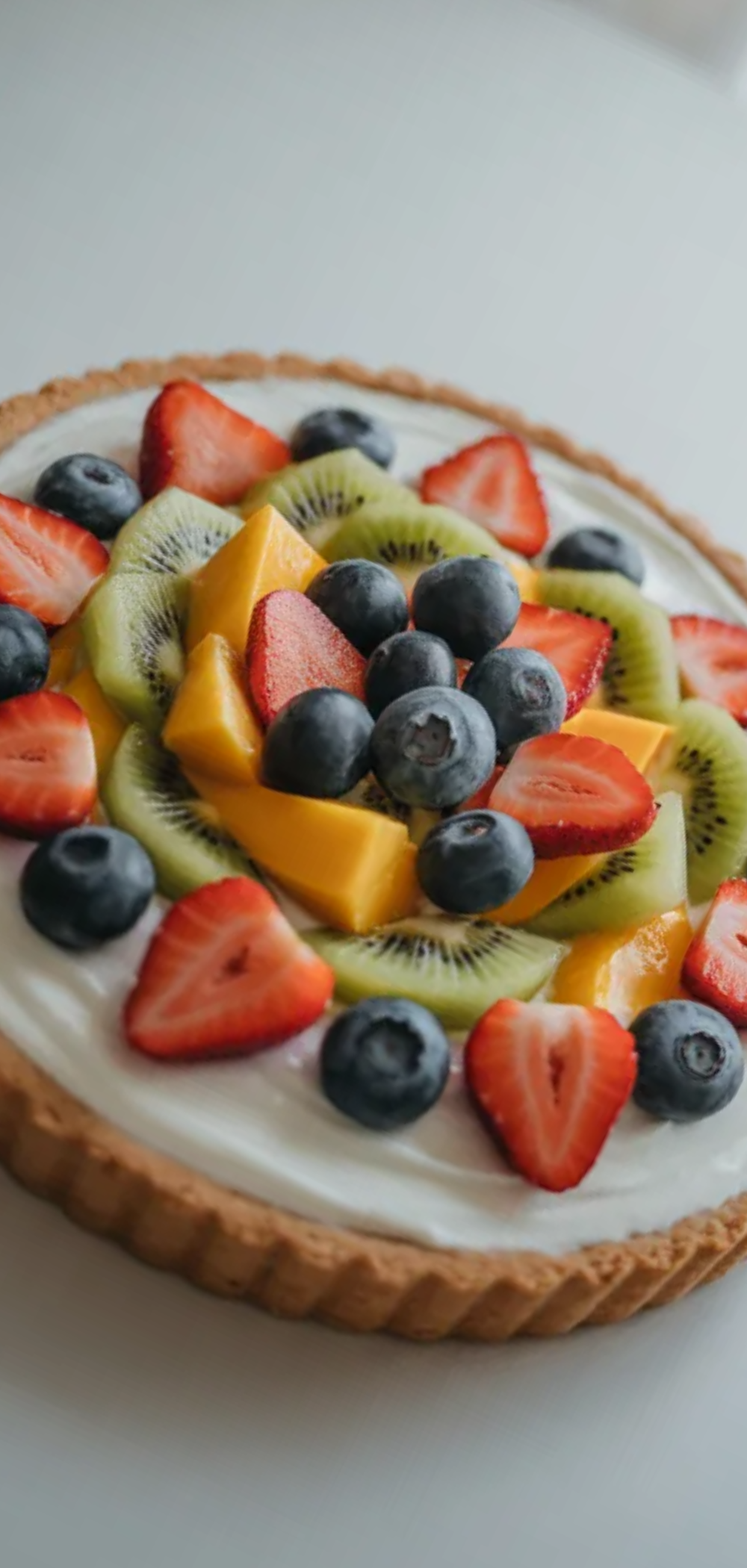Creamy Greek yogurt fruit tart topped with fresh berries and kiwi on a clean white background
