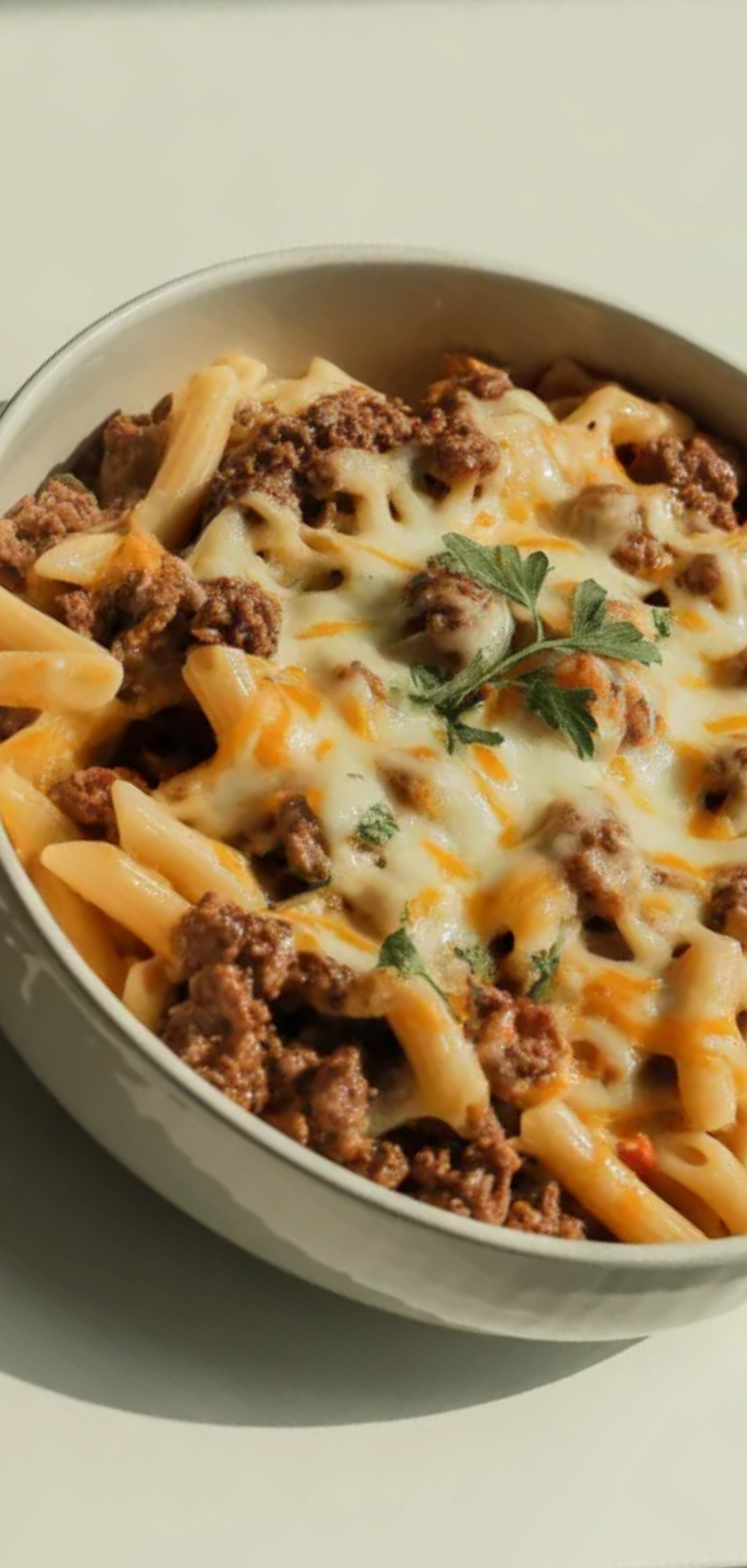 Creamy cheesy beef pasta with penne in a white dish, minimal shadows, food blogger style on a bright white background
