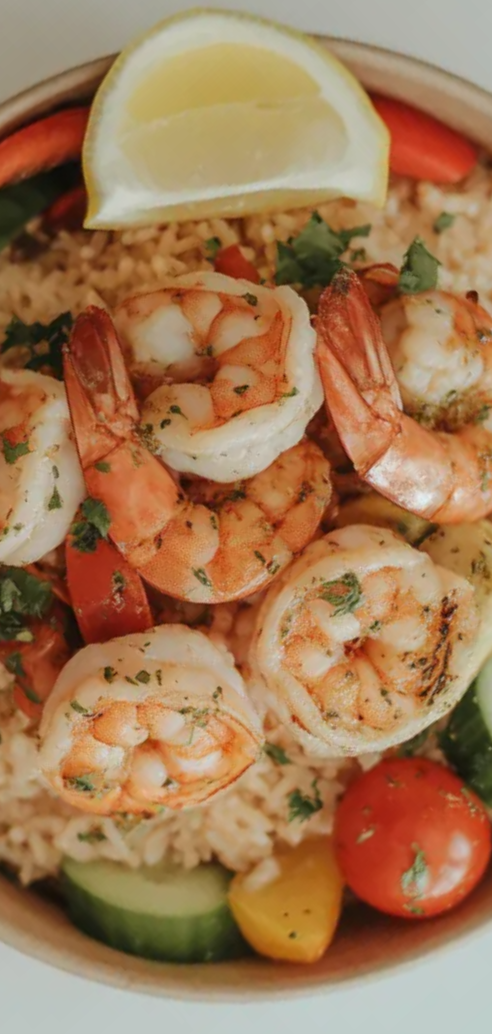 Juicy grilled shrimp on fluffy rice with fresh vegetables and parsley garnish in a bright, clean bowl.