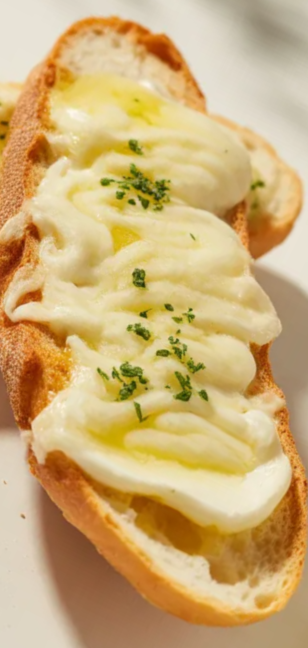 Crispy homemade garlic bread with melted cheese and parsley in soft natural light