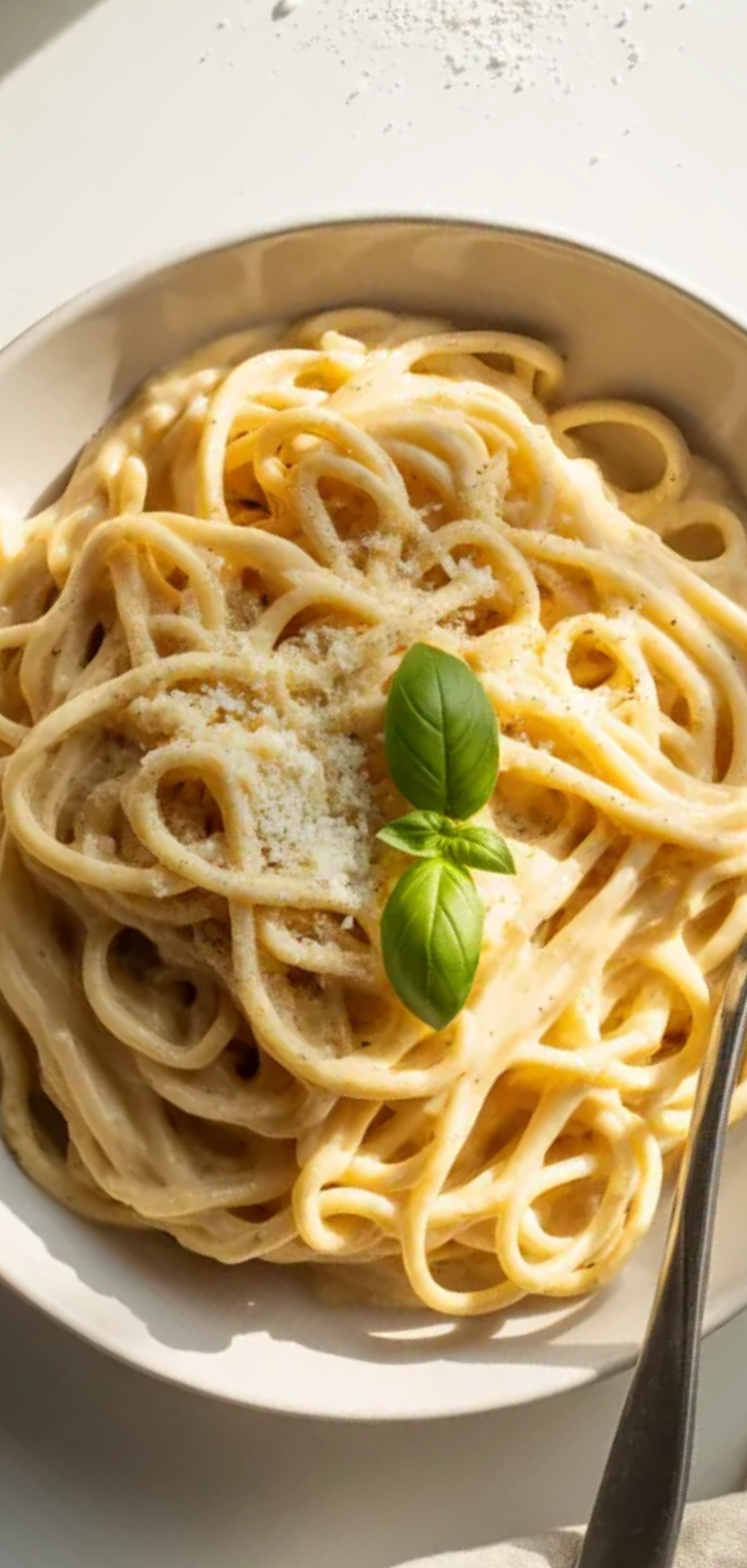 High protein cottage cheese pasta in a white ceramic bowl, topped with herbs and cheese, with a clean, bright, minimalist food photography setup on a white table.