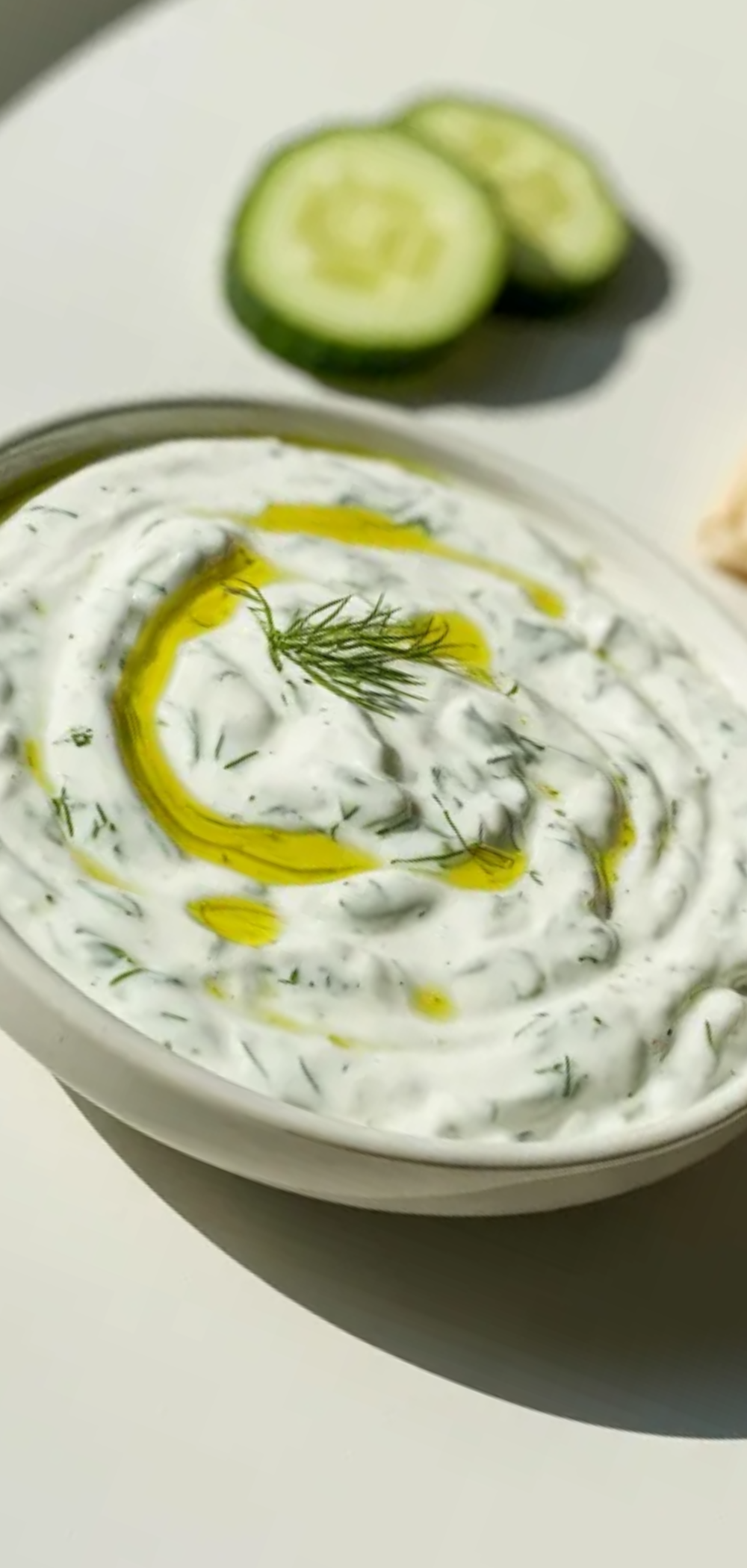 Homemade tzatziki sauce made with Greek yogurt, cucumber, and herbs, styled on a white background with minimal food photography setup