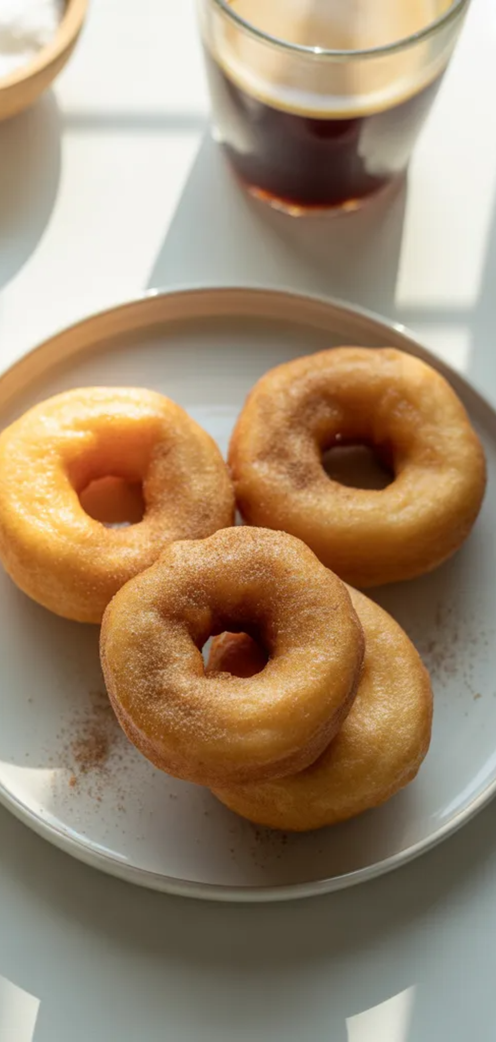 Homemade air fryer donuts golden and light with sugar topping styled on a white table in natural soft lighting