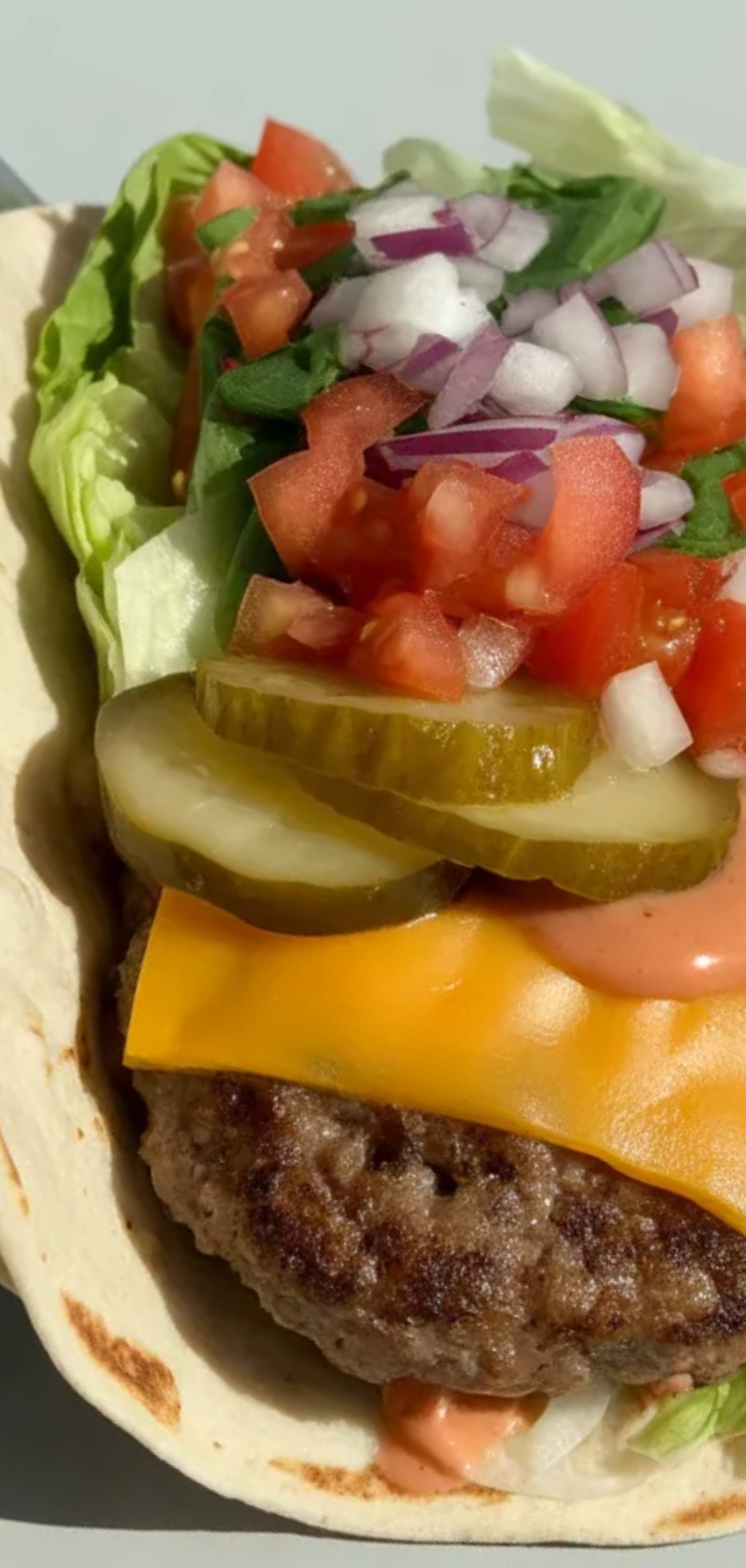 “Bright and clean food photography of a Smash Burger Taco with crispy edges, melty cheese, and colorful vegetables on a white surface.”