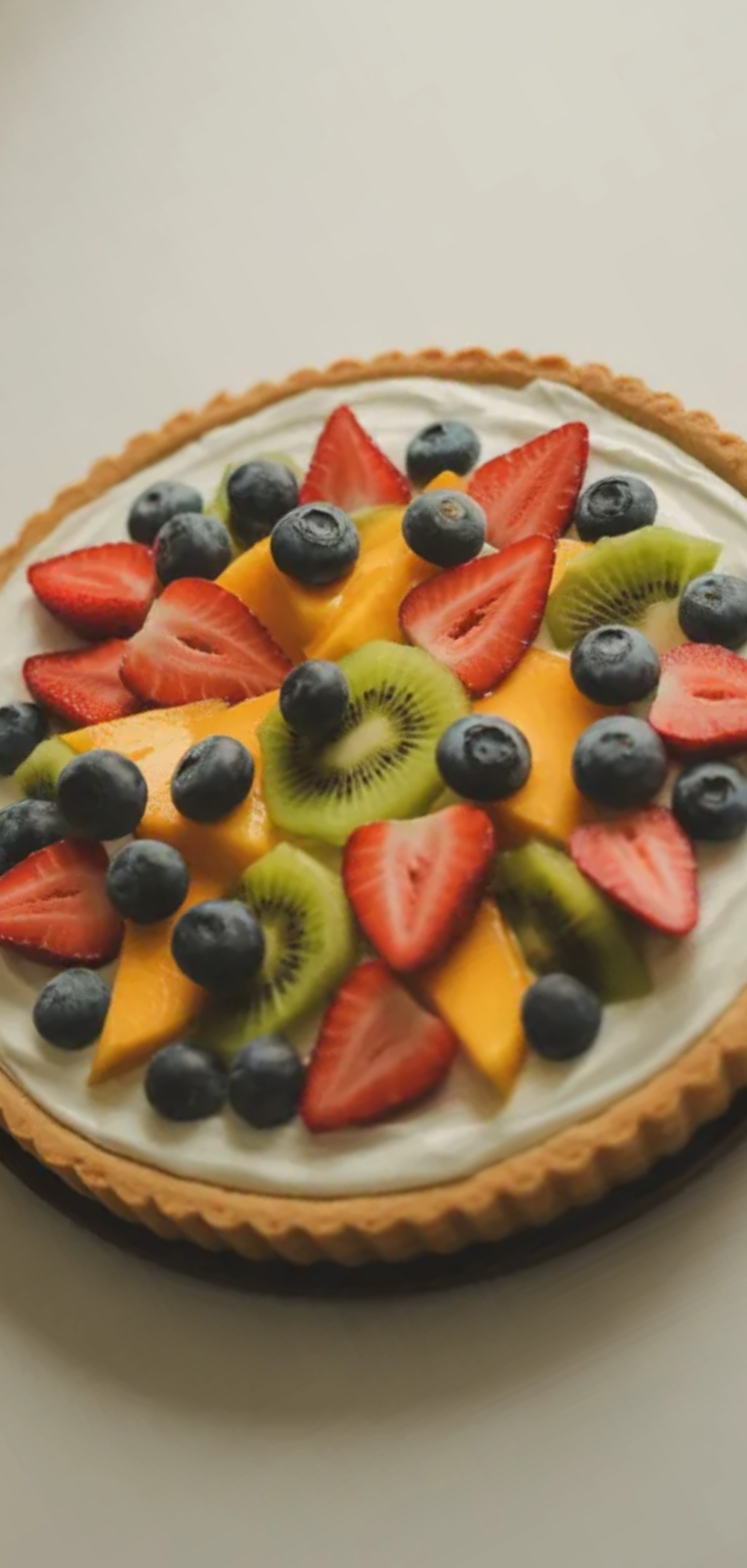 Homemade yogurt fruit tart with fresh summer fruits simple white table soft natural lighting
