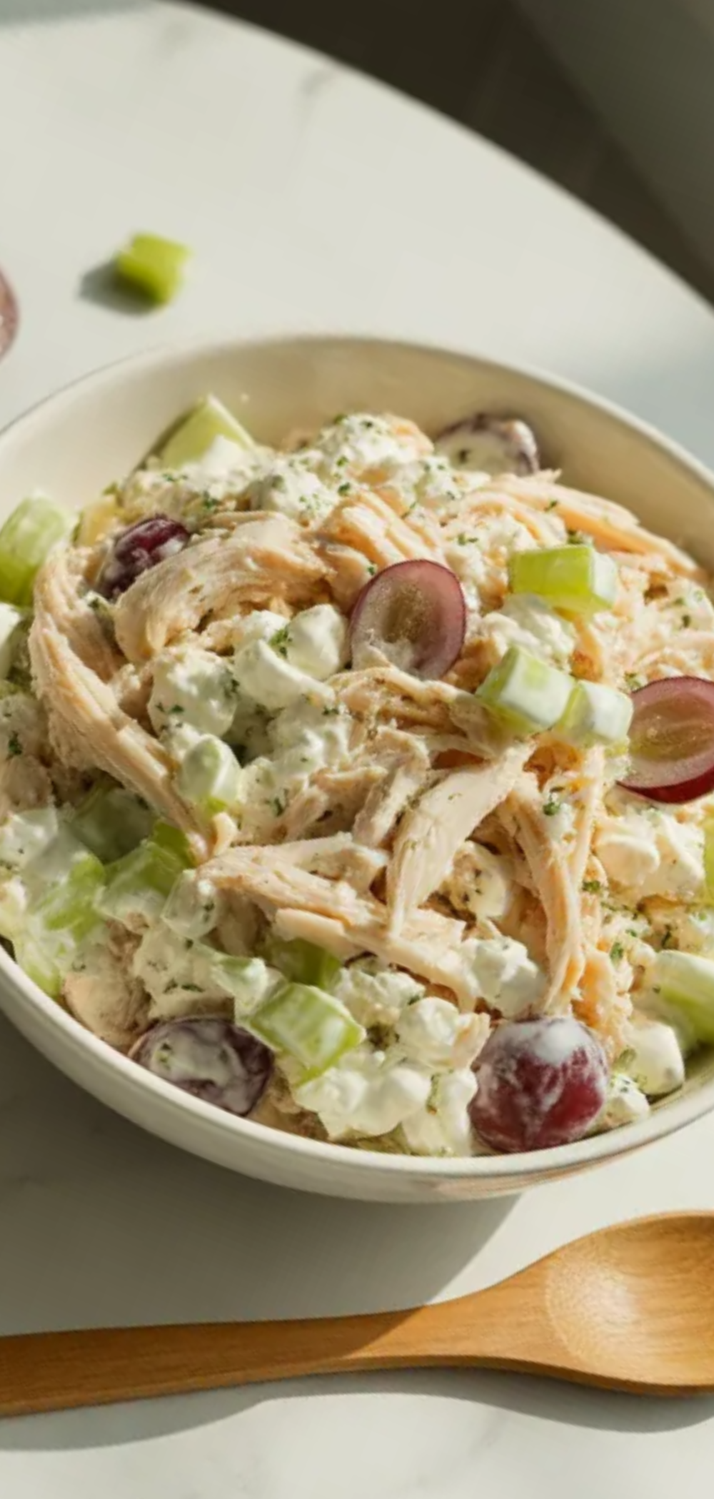 Light and creamy cottage cheese chicken salad with crunchy celery and sweet grapes, styled on a white table with soft natural lighting for food photography

