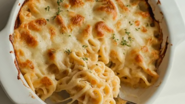 Creamy cheesy pasta bake in a white dish with golden melted cheese on top on a clean white table