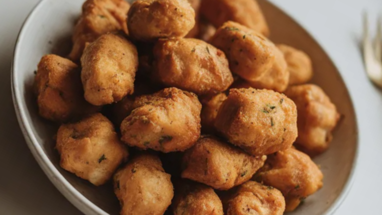 Crispy air fryer chicken bites served in a white bowl on a clean white table with dipping sauce on the side
