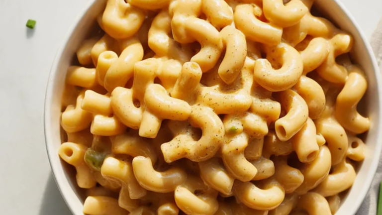 Creamy healthy mac and cheese in a white bowl on a clean white table with soft natural lighting