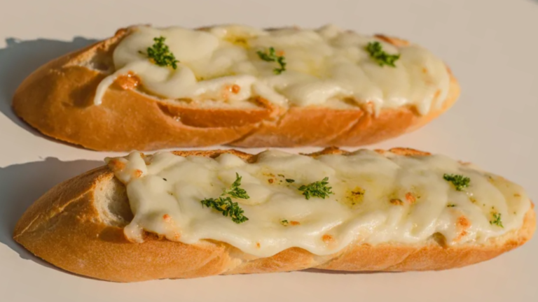 Simple cheesy garlic bread on a white table with melted mozzarella and garlic butter