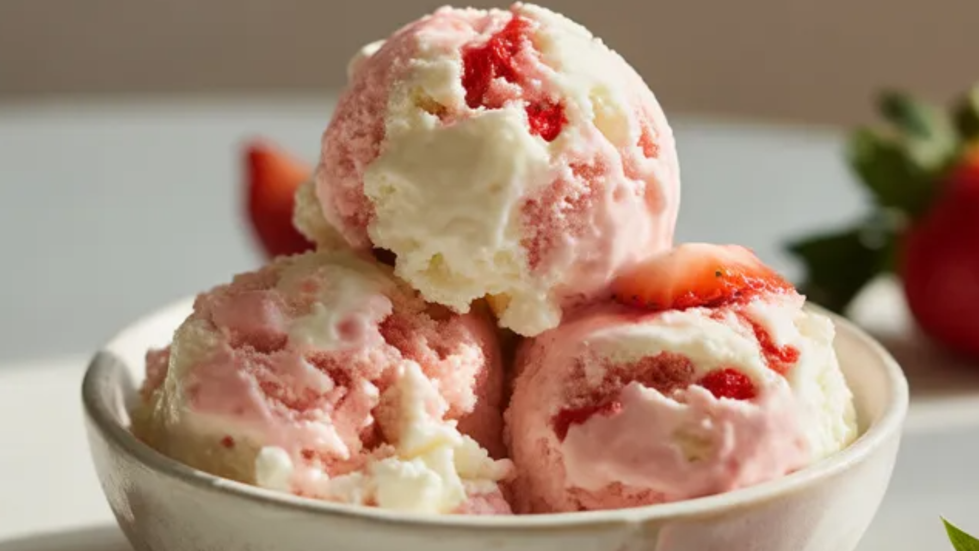 Strawberry cottage cheese ice cream in a white bowl on a clean white table with fresh strawberry slices and a spoon, natural soft lighting and creamy texture visible
