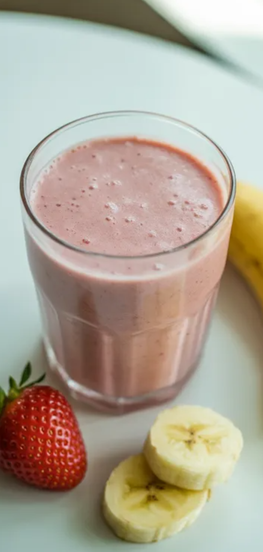Healthy strawberry banana smoothie served in a glass jar, smooth texture visible, decorated with strawberry and banana slices on top, food blogger style.